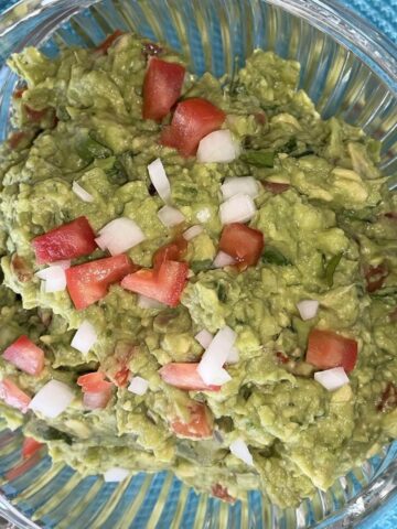 guacamole in a bowl garnished with tomato and onion