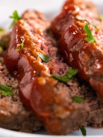 three sliced of glazed meatloaf garnished with chopped parsley