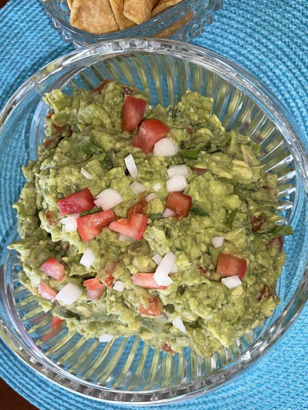 guacamole in a bowl garnished with tomato and onion