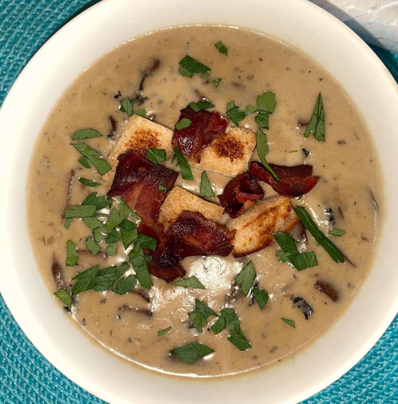 cream of mushroom soup in a bowl garnished with bacon and croutons
