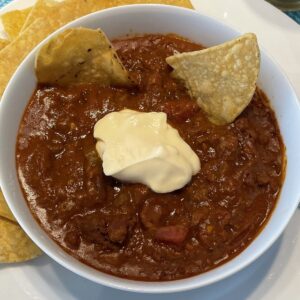 beef chili with beans in a bowl topped with sour cream