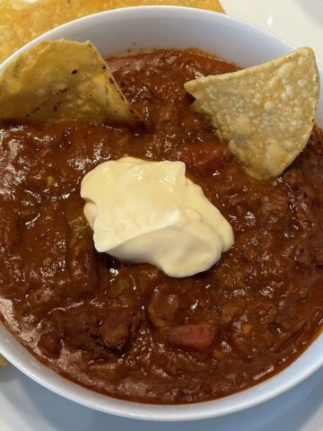 beef chili with beans in a bowl topped with sour cream