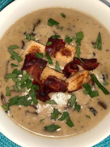 cream of mushroom soup in a bowl garnished with bacon and croutons