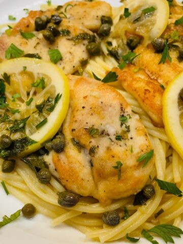 lemon chicken piccata over spaghetti with capers and lemon slices