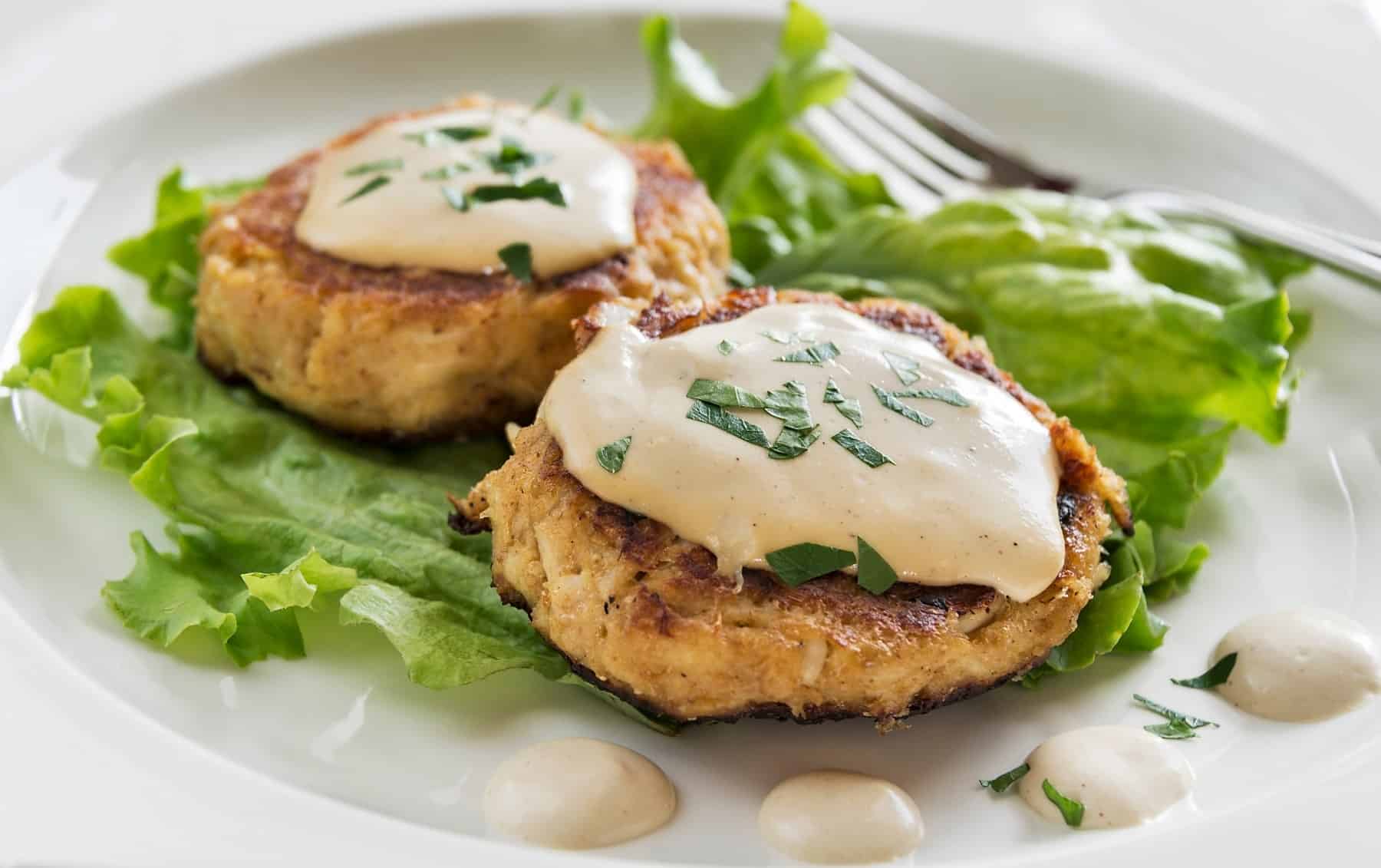 maryland crab cakes on a bed of lettuce topped with remoulade sauce