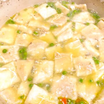 southern rolled dumplings cooking in a pot of broth with peas and chicken