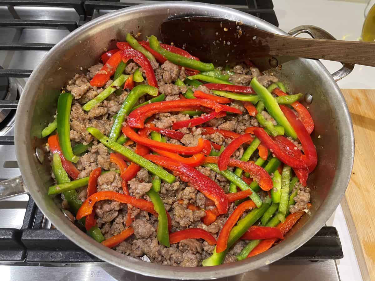 red and green bell pepper slices and italian sausage in a saucepan