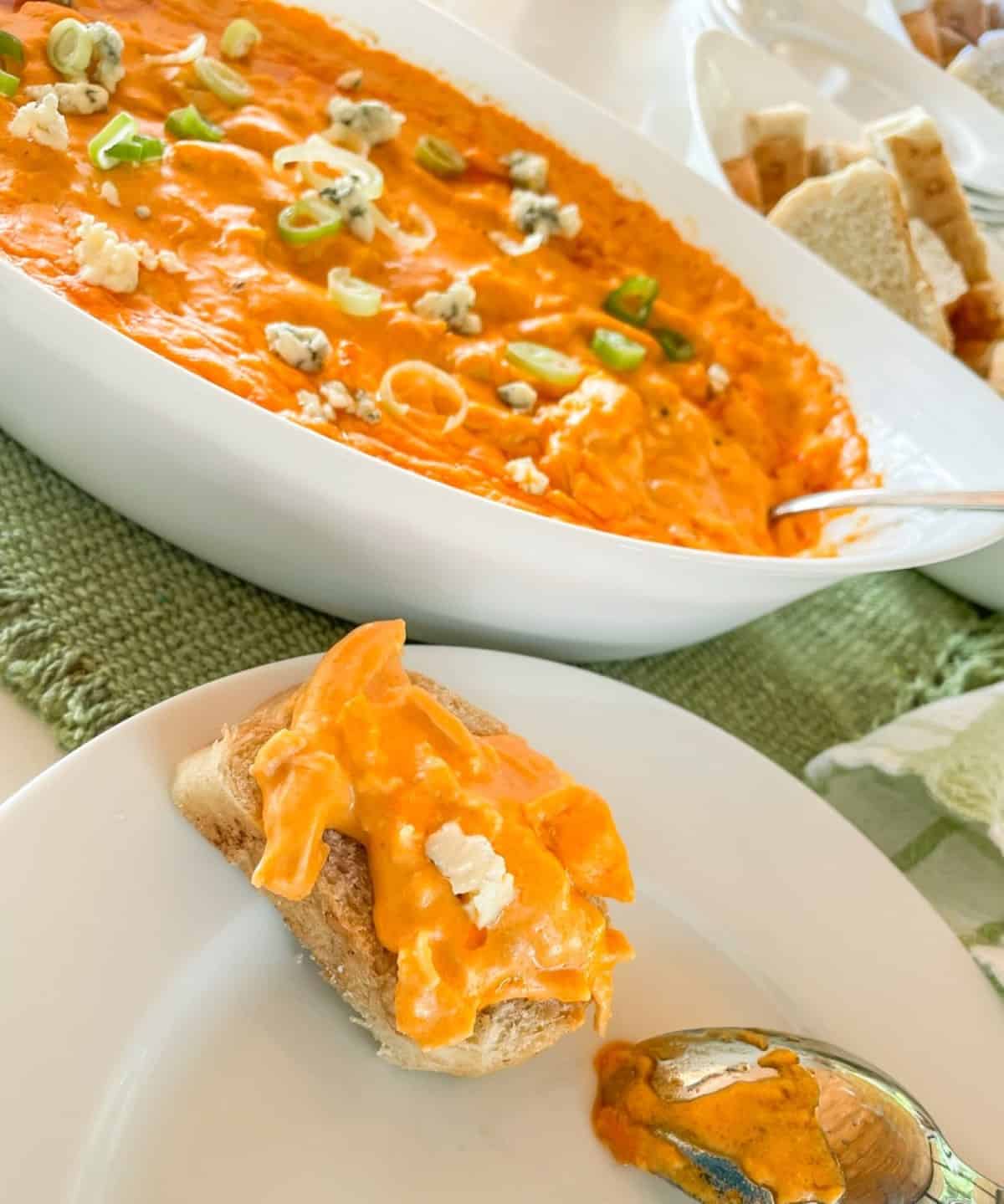 buffalo chicken dip in a baking dish with bread for serving