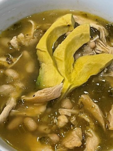 chicken chili verde in a bowl garnished with avocado slices