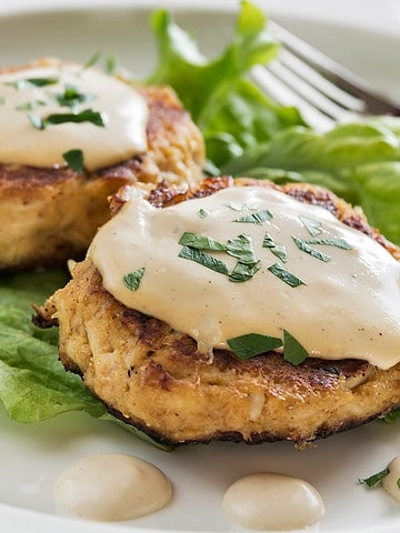 maryland crab cakes on a bed of lettuce topped with remoulade