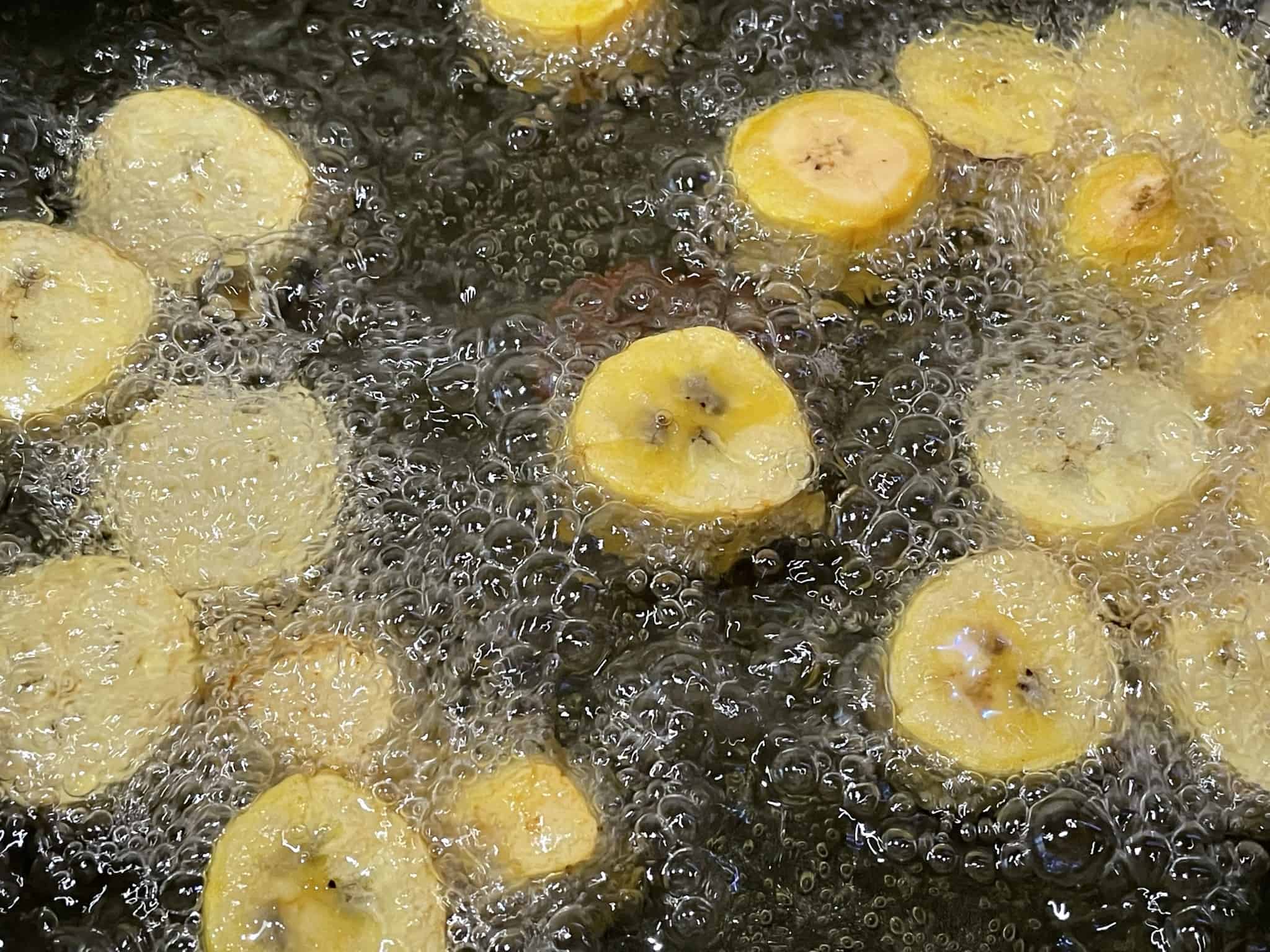 sliced plantains frying in oil