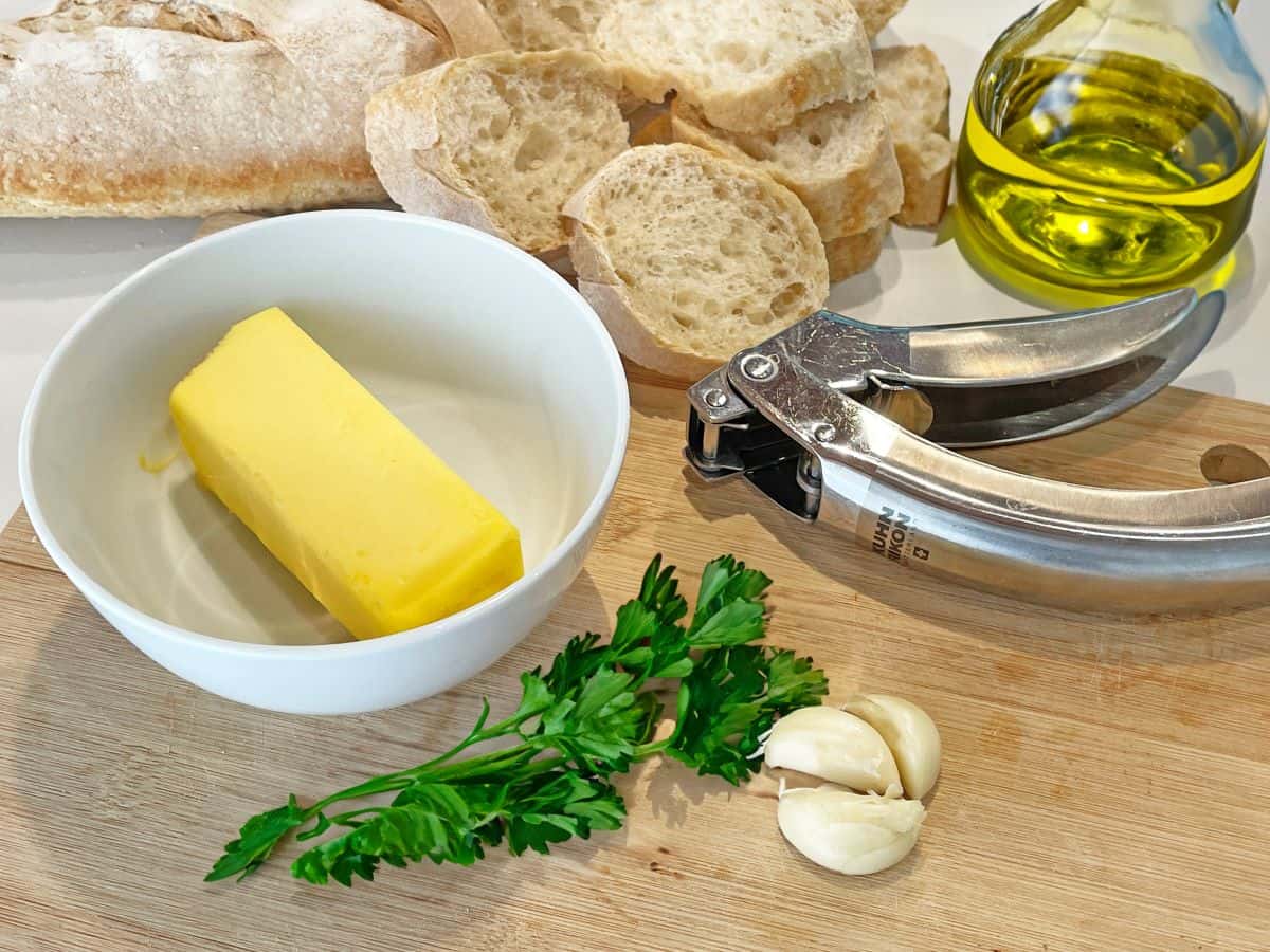 butter, parsley, garlic cloves, olive oil and sliced italian bread to make garlic bread