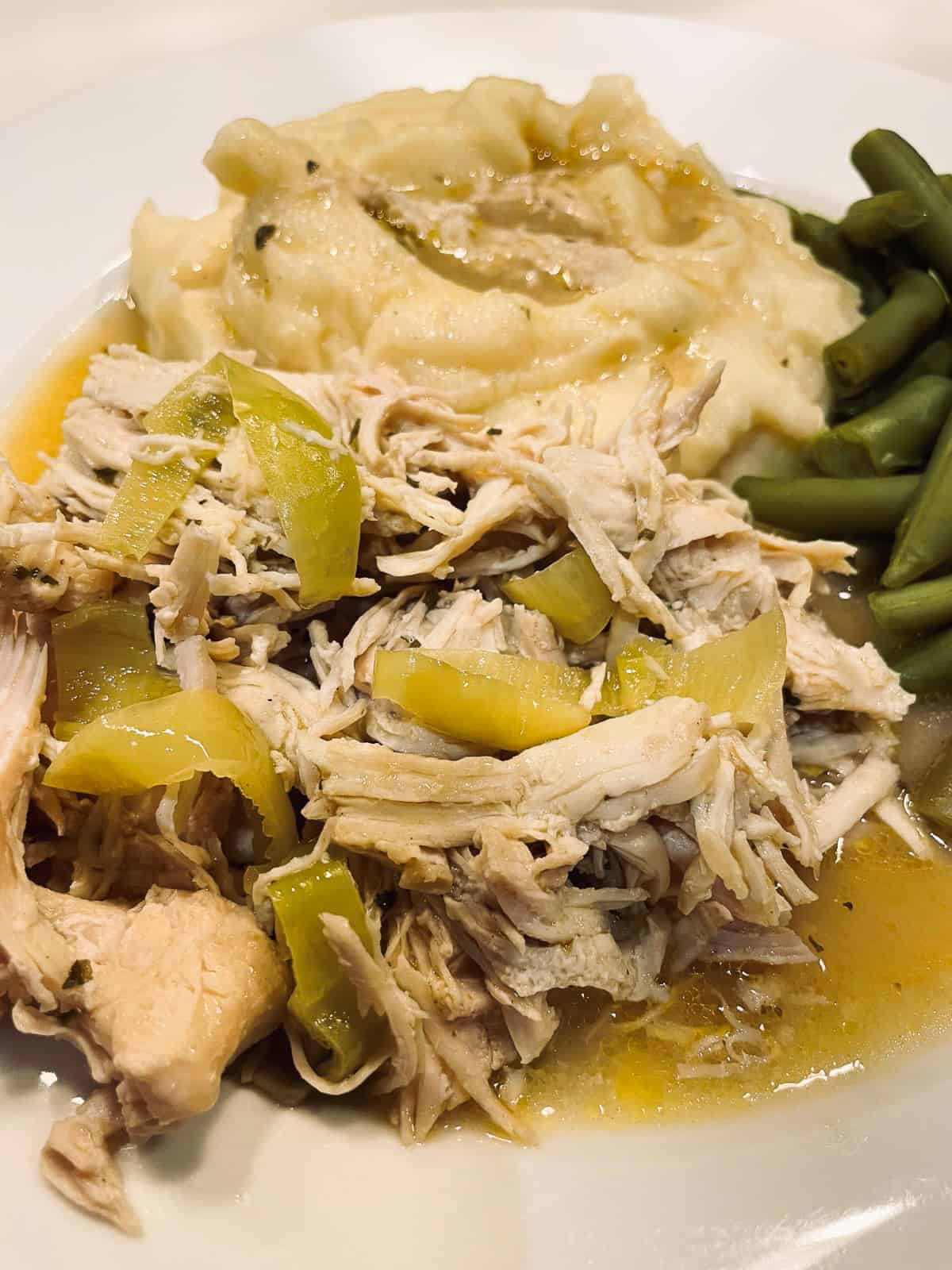 mississippi chicken  on a plate with green beans