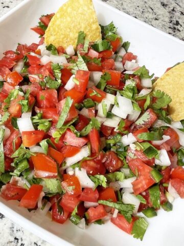 fresh salsa of tomato, jalapeno, garlic, onion, cilantro and lime juice in a bowl in tortilla chips