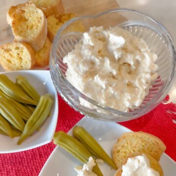 shrimp dip with cream cheese and sour cream in a bowl served with garlic bread and pickled okra