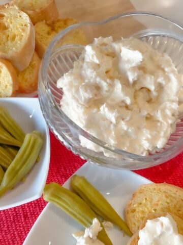 shrimp dip with cream cheese and sour cream in a bowl served with garlic bread and pickled okra