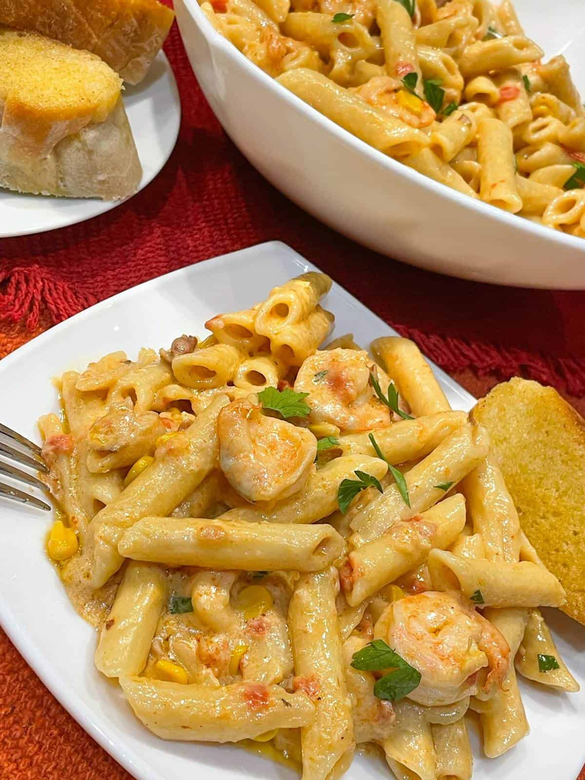 shrimp in spicy alfredo sauce with pasta on a plate with garlic bread