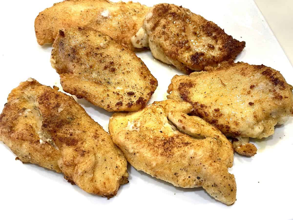 pan sauteed chicken breasts that were dusted in flour, resting on a plate