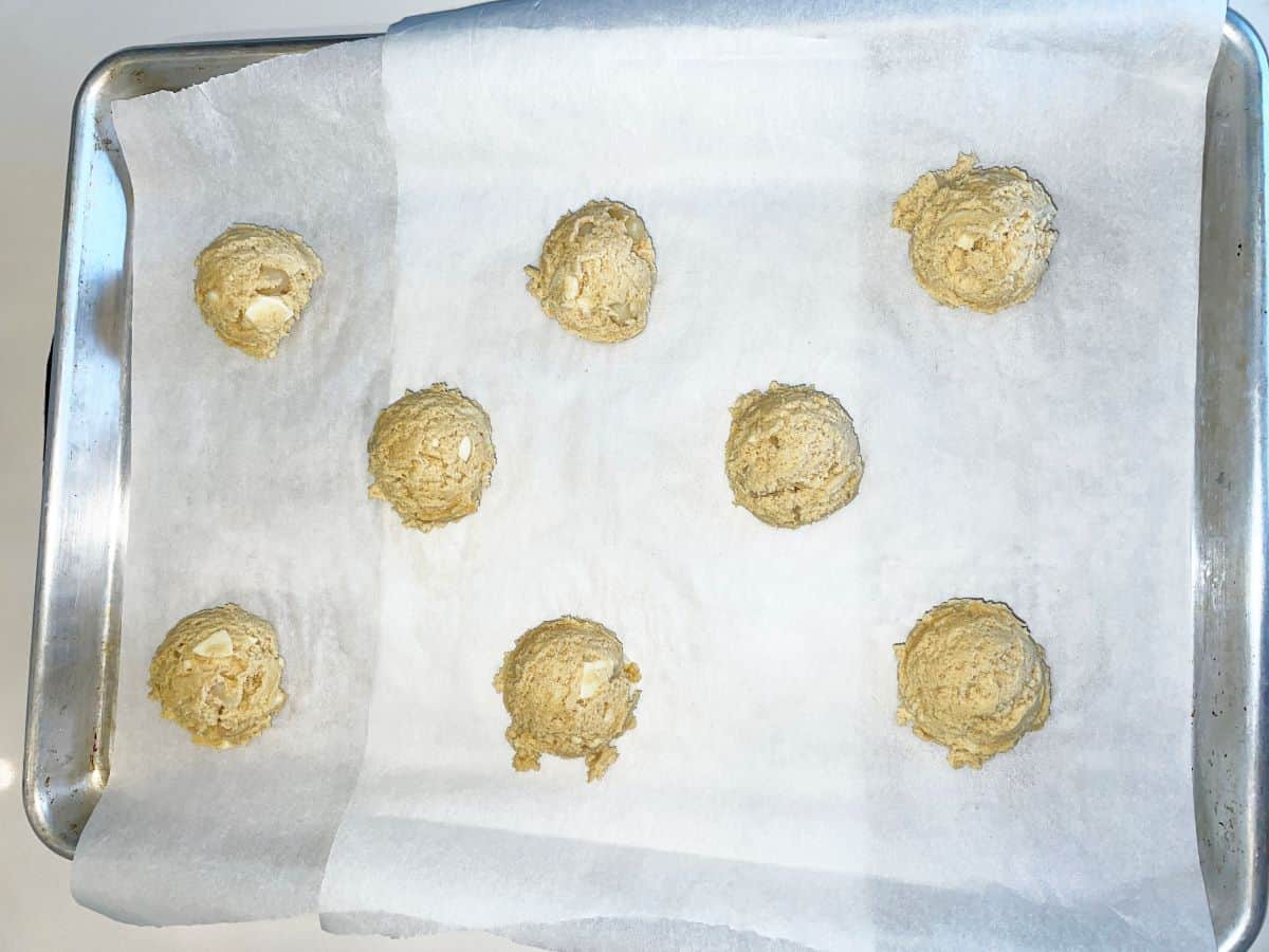 cookie dough scooped onto a baking sheet, eight cookies ready to go in the oven
